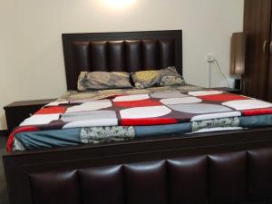 a bed with a leather headboard and pillows on it at Luxury 2BR Family Apt/Wi-Fi / Netflix in Islamabad