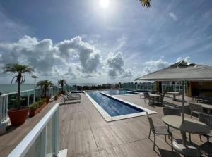 d'un balcon avec une piscine, des tables et des chaises. dans l'établissement Flat na Praia do Bessa Atlântico Norte 303, à João Pessoa