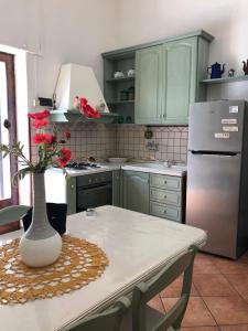 a kitchen with green cabinets and a table with a vase with flowers at A Uardia in Tora
