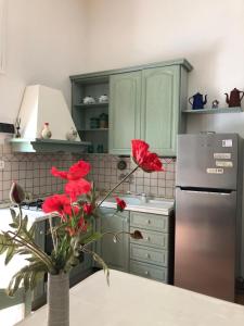 a kitchen with a refrigerator and red flowers in a vase at A Uardia in Tora
