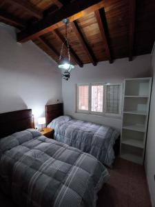 ein Schlafzimmer mit zwei Betten in einem Zimmer mit Holzdecken in der Unterkunft Vivi San Rafael, centrico, con cochera in San Rafael