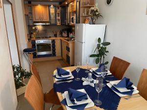 eine Küche mit einem Tisch mit blauen Servietten und einem weißen Kühlschrank in der Unterkunft SG chalupa MLÁZOVICE - WELLNESS v ceně in Mlázovice
