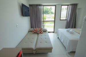 una camera da letto con un letto, un divano e una finestra di MANA BEACH EXPERIENCE by AFT Porto de Galinhas, Muro Alto a Porto De Galinhas Altre 34 foto