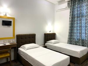 a room with two beds and a desk and a mirror at Hotel Republika Berat in Berat