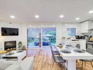 a kitchen and living room with a white table and chairs at V&VLLORET-VILLA CAMELIA gran villa para 12PAX, con aire acondicionado, piscina,casa árbol niños y ping-pong in Vidreres