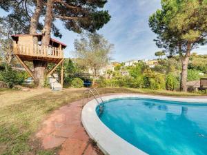 a tree house with a deck next to a swimming pool at V&VLLORET-VILLA CAMELIA gran villa para 12PAX, con aire acondicionado, piscina,casa árbol niños y ping-pong in Vidreres