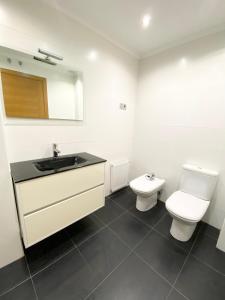 La salle de bains blanche est pourvue d'un lavabo et de toilettes. dans l'établissement Blue house Bermeo, à Bermeo
