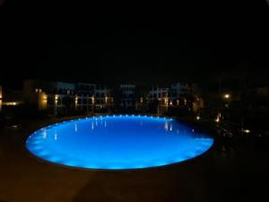 een groot blauw zwembad 's nachts met gebouwen op de achtergrond bij Lovely first floor tow bed rooms overviewing circular pool in Talabay Aqaba in Aqaba