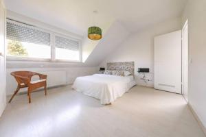 een witte slaapkamer met een bed en een stoel bij Neue Wohnung in der Nähe von Trier in Korlingen