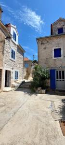 an old stone building with a blue door on a street at Villa Tomitorija in Kaprije
