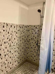 een badkamer met een douche en een betegelde muur bij beach room in Snogebæk
