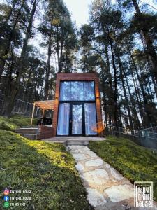 a small house with a window in the grass at Cabañas Boutiques TinyChillHouse in Mineral del Chico
