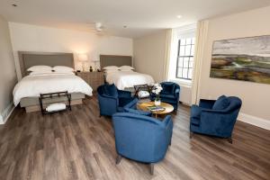 a hotel room with two beds and blue chairs at The Glenerin Inn in Mississauga