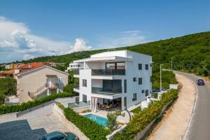 a white house with a swimming pool next to a road at Luxury apartment Marco Polo with a private swimming pool with salt sea water in Punat