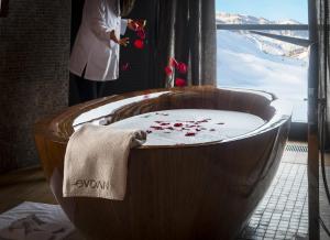 a wooden bath tub with a woman standing next to a window at Shahdag Hotel & Spa in Shahdag