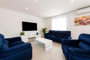 - un salon avec deux canapés bleus et une télévision dans l'établissement Villa Anny, à Mokošica