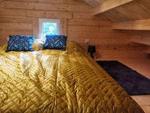 Una cama en una cabaña de madera con almohadas azules. en Puchata Chata - Mazury, en Pozezdrze