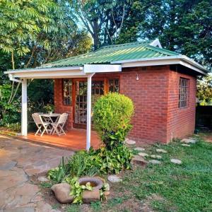 a small red brick house with a green roof at Woodgate Cottage in Howick