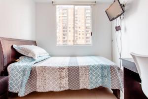 um quarto com uma cama com um cobertor e uma janela em Acogedora habitación en un punto central de Bogotá em Bogotá