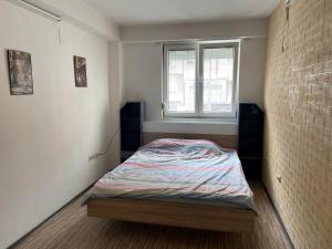 um pequeno quarto com uma cama e uma janela em Donna em Skopje