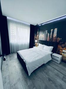 a bedroom with a large white bed with a city backdrop at The Garden Apartment in Oradea