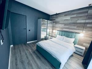 a bedroom with a large bed and a wooden wall at The Garden Apartment in Oradea
