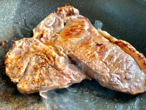 dos trozos de carne cociéndose en una sartén en Minamiaso STAYHAPPY - Vacation STAY 57924v, en Shimoda