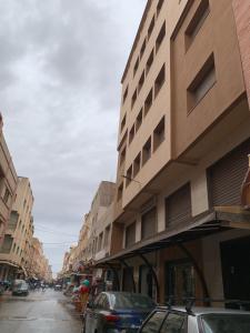 une rue de la ville avec des voitures garées à côté de grands bâtiments dans l'établissement اقامة السعادة, à Monte ʼArrouit