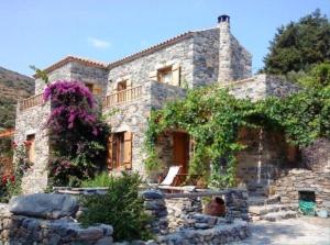 a large stone house with flowers in front of it at Neromylos in Agia Pelagia