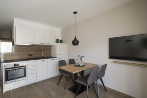 cocina con mesa y TV en la pared en Residence Sonja - Apartment Pinus, en Rablà