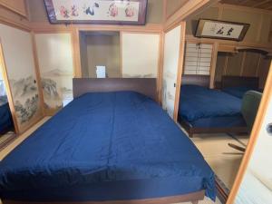 ein Schlafzimmer mit einem blauen Bett in einem Zimmer in der Unterkunft Inadani Villa - Vacation STAY 14589 in Ina