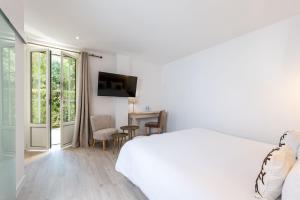 a white bedroom with a bed and a table and chairs at Hôtel Beau Site - Cap d'Antibes in Antibes