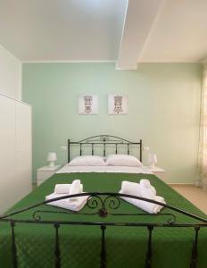 a bedroom with a green bed with towels on it at B&B Marco Polo in Terrasini