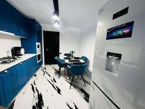 a kitchen with blue cabinets and a table with blue chairs at Apartament Plaja Neversea in Constanţa