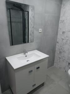 Baño blanco con lavabo y espejo en Oporto Sea Rooms en Oporto