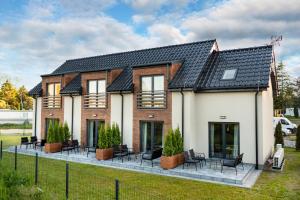 a house with chairs and tables in front of it at lotniarzy 15 domy z widokiem na morze in Trzęsacz