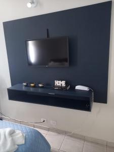 uma prateleira preta com uma televisão na parede em Apartamento 1010 em Goiânia