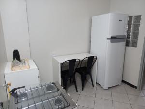 a kitchen with two black chairs and a white refrigerator at Apartamento 1010 in Goiânia +17 photos
