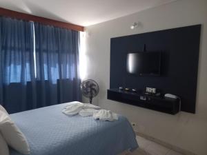 a bedroom with a bed and a flat screen tv at Apartamento 1010 in Goiânia