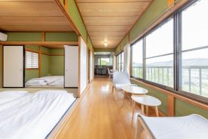 a room with a bed and chairs and windows at Hot spring inn Nonbiri -Ihatov Nakaizu- - Vacation STAY 51852v in Izu