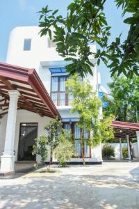 un bâtiment blanc avec des arbres devant lui dans l'établissement Sanmi Home Rentals Battaramulla, à Battaramulla