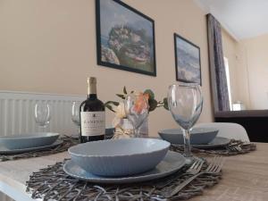 a table with a bottle of wine and plates and glasses at IL TRAMONTO APARTMENTs 2 in Kanali