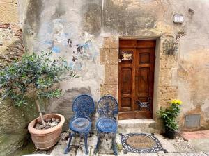 dos sillas sentadas frente a un edificio con una puerta en Casa Marghera House Winery Bikes, en Pitigliano