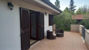 a patio with two chairs and an open door at Domus Claudio in Villam in Pomezia