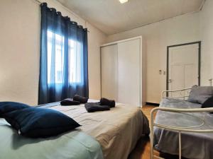 een slaapkamer met 2 bedden en een raam met blauwe gordijnen bij L'hypercentre - Clim - Terrasse - WIFI in Miramas