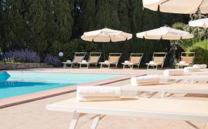 una piscina con sillas y sombrillas junto a una piscina en B&B Villa il Poggetto, en Venturina Terme