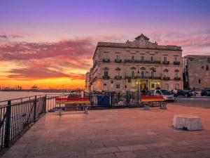a building with benches in front of a sunset at Sedici Scalini in Taranto