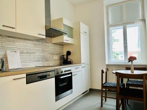 uma cozinha com armários brancos, uma mesa e uma janela em Cosy & Central - Free Parking - Free Netflix em Viena