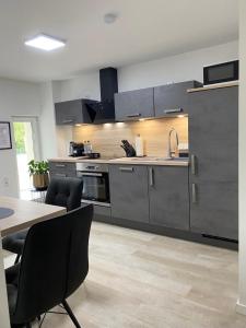 a kitchen with gray cabinets and a table and chairs at QT Apartments Detmold in Detmold