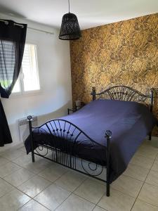 una camera da letto con un letto con un piumone blu e carta da parati dorata di Charmante villa dans un lotissement très calme a Béziers